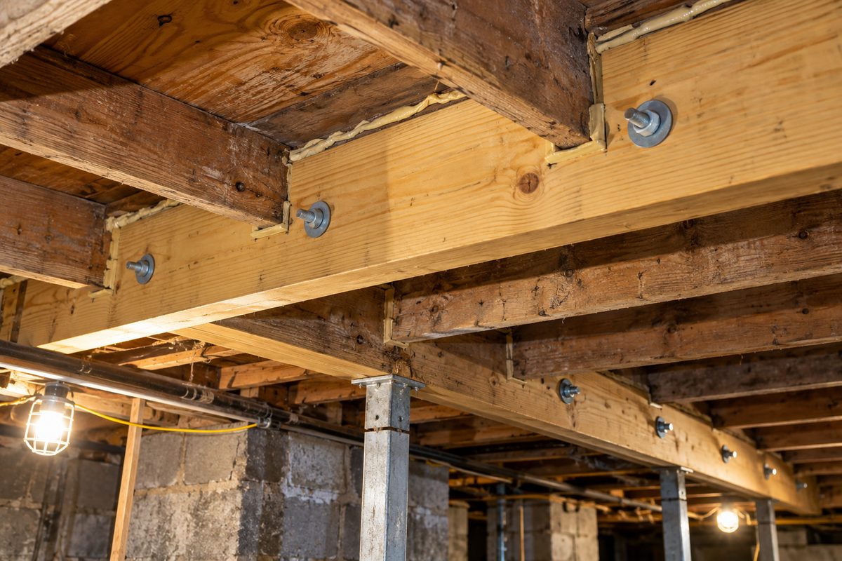 New structural floor joist sistered against existing framing with heavy bolts and adhesive